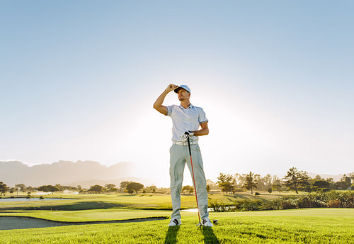 Male golfer holding golf club on field