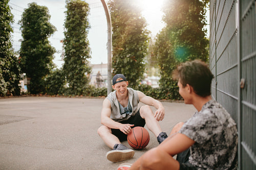 Young basketball players sitting on court and smiling