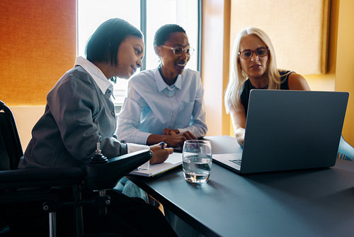 Diverse team working together around a laptop in a modern office