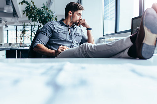 Thoughtful man sitting with feet on table