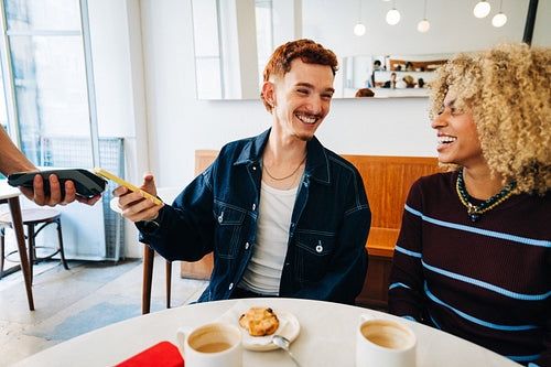Young friends paying in a cafe