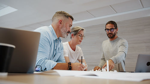 Design professionals combing their creativity for a wind energy project, using blueprint drawings and 3D modeling