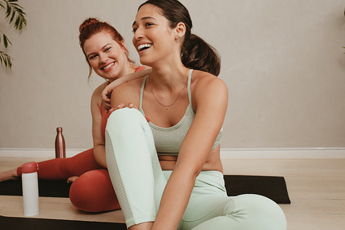 Smiling women friends relaxing after fitness training