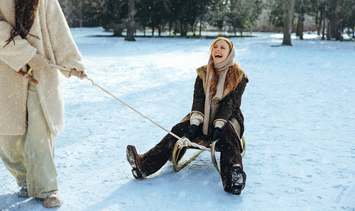Women enjoy sledding together in a snowy park