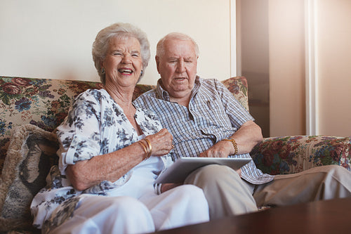Happy elderly couple with digital tablet at home