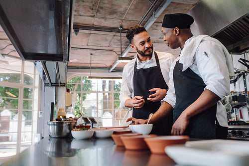 Chefs talking while cooking food in commercial kitchen