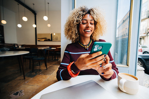 Young woman smiling with smartphone in cozy cafe