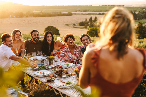 Woman taking picture of friends having dinner party