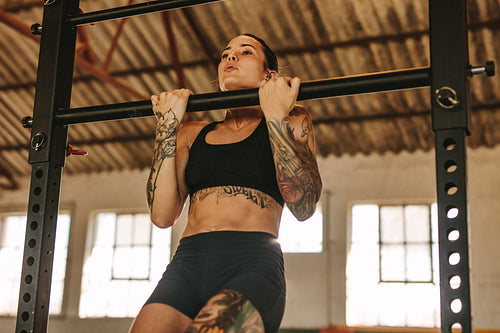 Woman doing pull up workout in empty factory shade