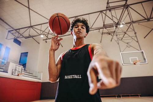 Young athlete spinning basketball indoors