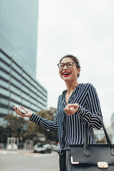 Happy businesswoman waiting for taxi on the street
