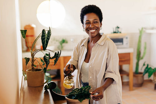 Nurturing indoor plants: Brazilian woman carefully watering and spraying potted plants