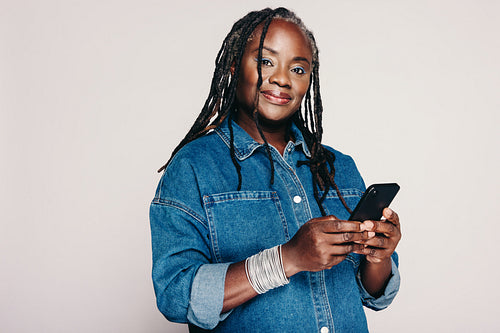Beautiful black woman holding a smartphone in a studio