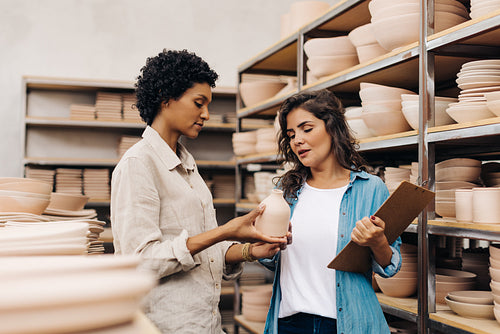 Two female ceramists discussing one of their handmade products