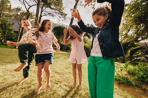 Children playing outdoors joyfully under sunlight in a beautiful garden