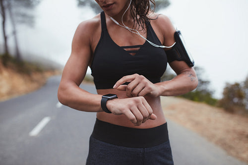 Woman adjusting her smart watch while exercising outdoors