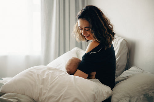 Mother breastfeeding baby in bed