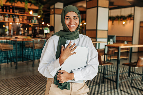Happy woman with a headscarf smiling at the camera in a cafe