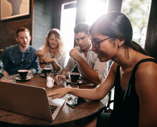 Group of friends in cafe watching something online on laptop