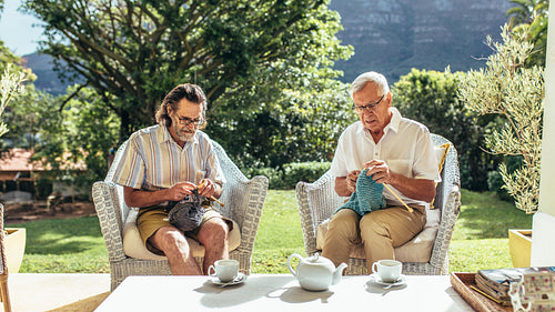 Two old men knitting in patio