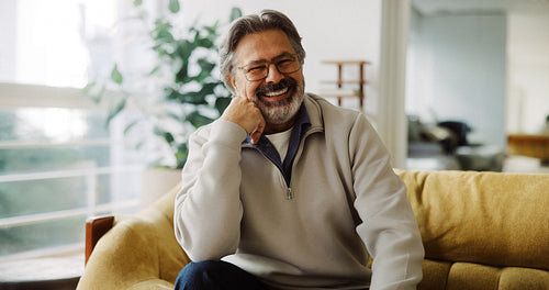 Sitting senior man enjoys leisure on a couch at home