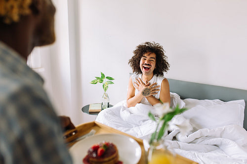 Surprised gay man receiving breakfast in bed from his lover