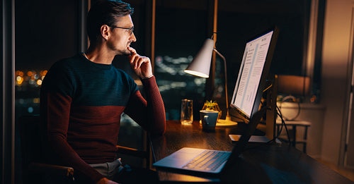 Business man using a computer and a laptop while working late in his office