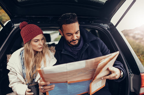 Young couple using map on a road trip