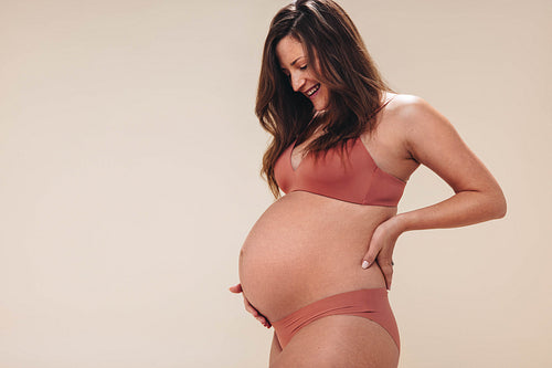 Embracing pregnancy: Mom-to-be smiling at her third trimester baby bump