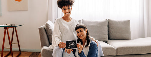 Lesbian mothers-to-be holding up their ultrasound scan