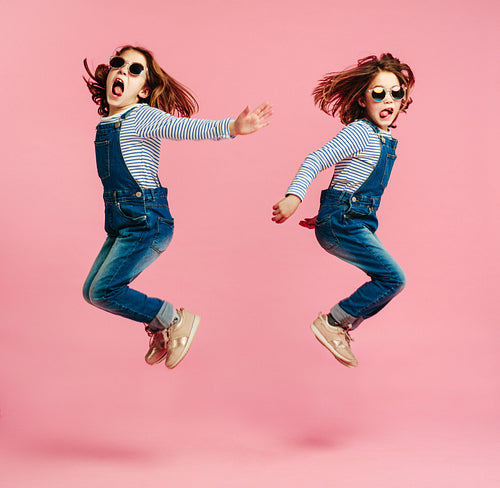 Twin sisters jumping in fashion outfits