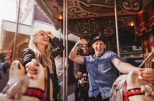 Smiling couple on horse carousel ride at fairground