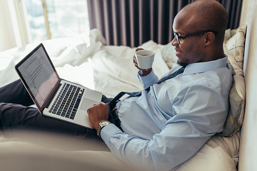 Businessman working on laptop computer lying on bed