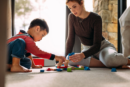 Mother and son playing with building blocks at home