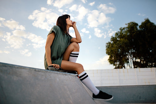 Girl sitting on a skateboard in the park