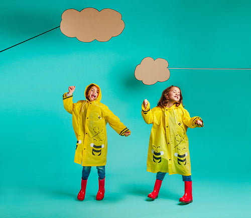 Cute twins girls dancing in raincoats