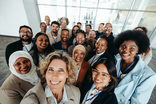 Multiethnic corporate team taking a group selfie together inside an office building