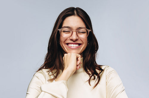 Woman with glasses laughing and resting chin