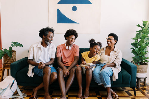 Family laughing together in their home, having fun on a couch