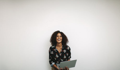 Portrait of a laughing woman entrepreneur holding a laptop