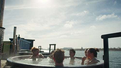 Celebration and sunshine bring friends together in an outdoor hot tub at the waterfront