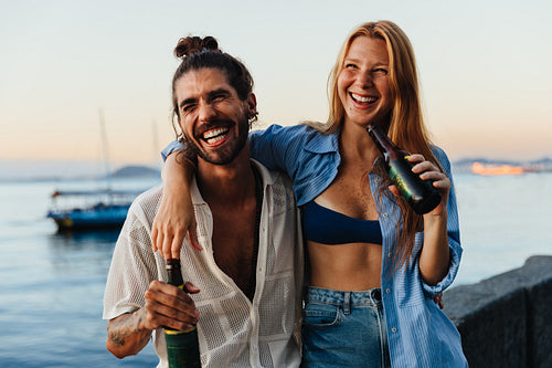 Young couple enjoying summer sundowners by the seaside