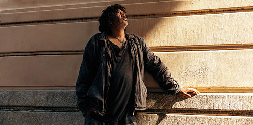 Thoughtful homeless man looking up outdoors