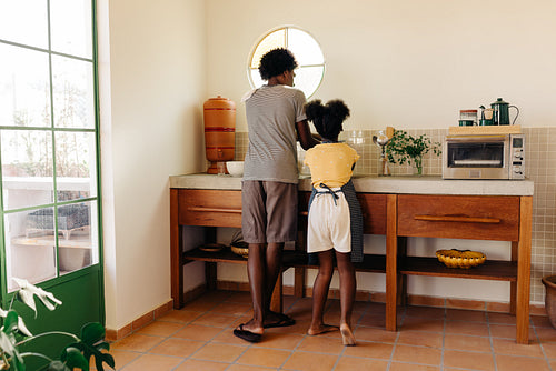 Two siblings mixing baking ingredients together at the kitchen sink, using clay filter water