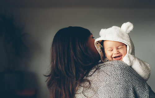 Cute little boy smiling in his mother's arms