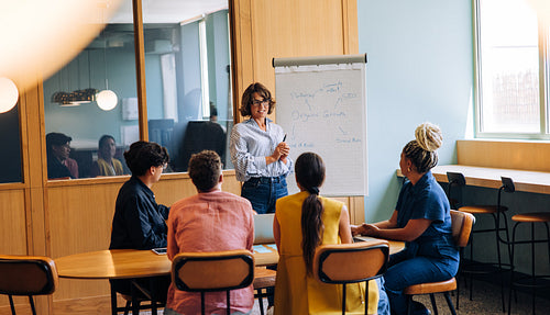 Team gathered around during a presentation focusing on chart in conference room