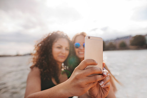 Women taking selfie with smart phone by the lake