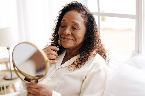 Mature woman using a jade roller for her anti-aging skincare routine