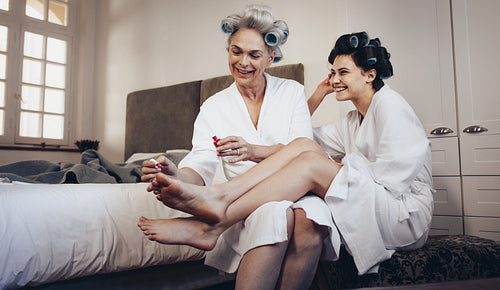 Mother and daughter grooming at home doing pedicure