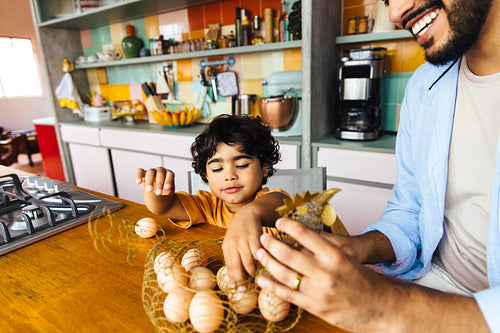 Smiling father and child arranging fresh eggs in a colorful kitchen setting